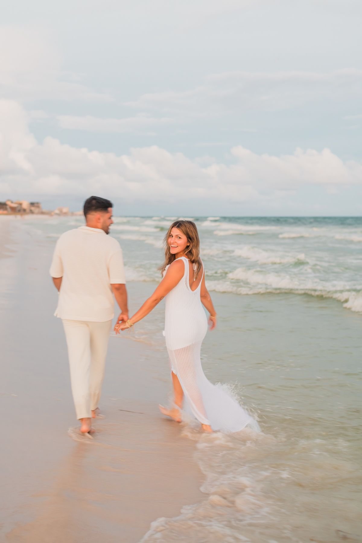 Karla y William caminando de la mano por la playa